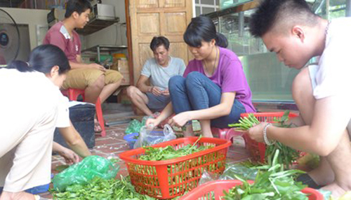 Ngân (áo tim) tranh thủ thời gian làm việc tại nhà hàng để giúp đỡ bố mẹ. Ảnh: Tiền phong.